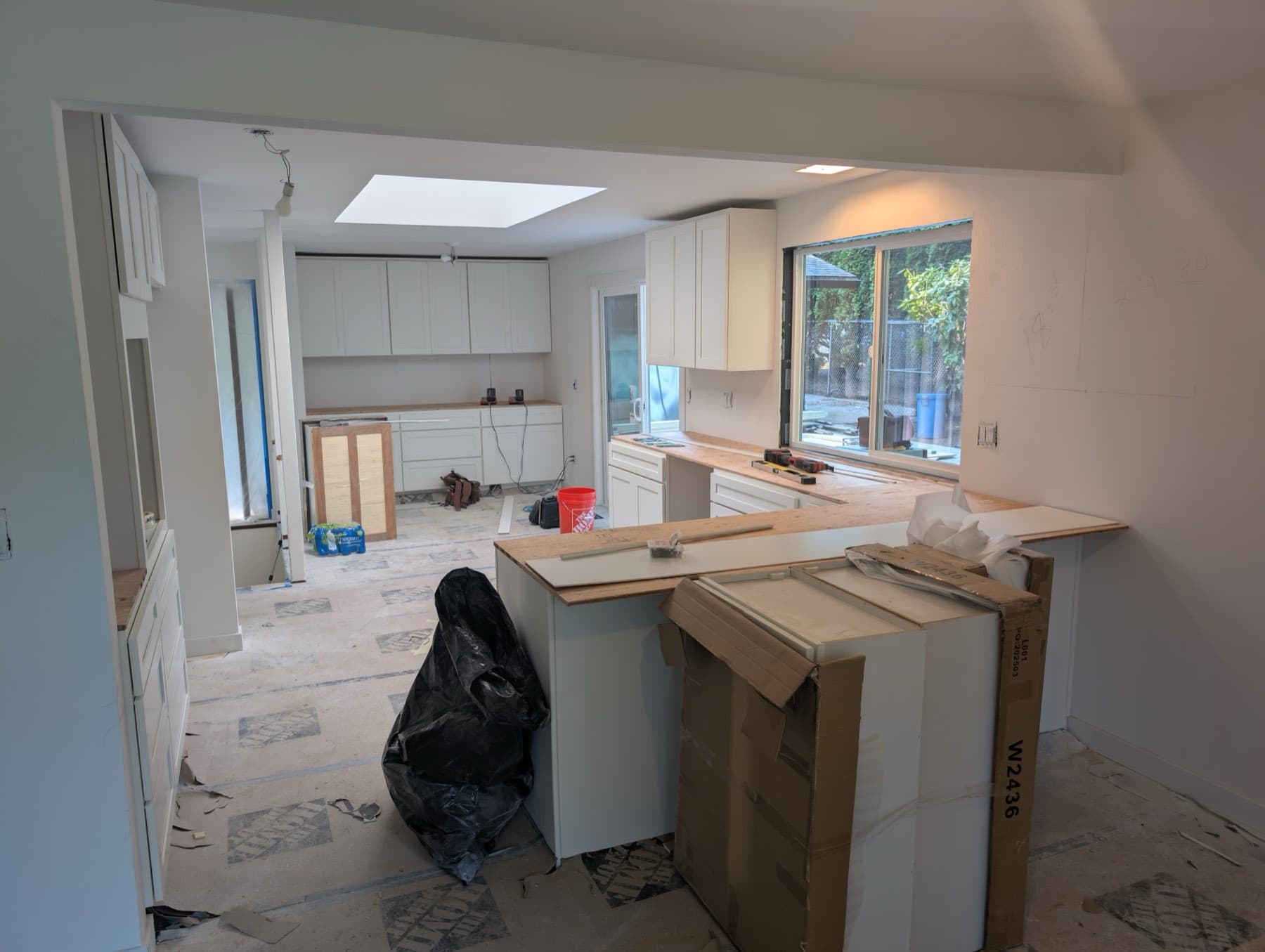 The kitchen mid-installation, cabinet carcasses in place under a new skylight.