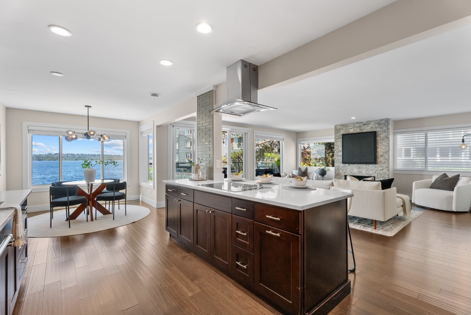 The kitchen island under a steel extractor hood, the dining corner and living room beyond it.