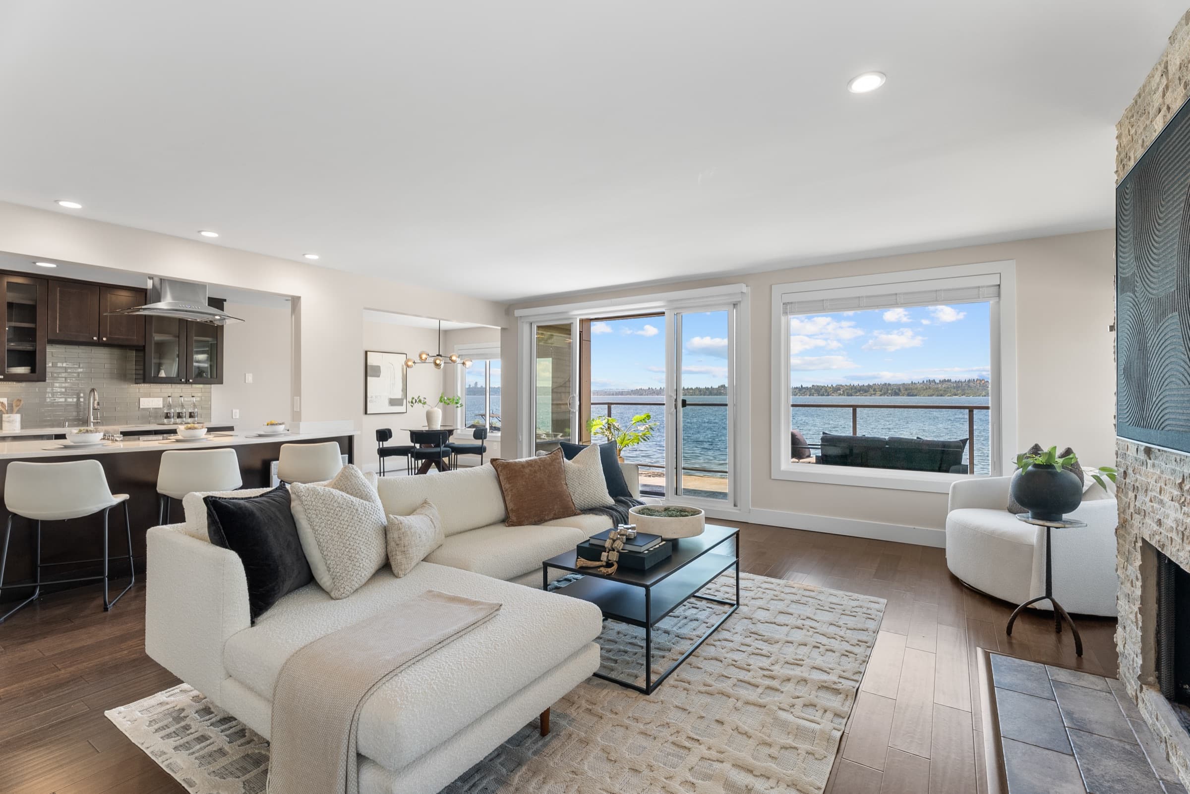The staged living room, open to the kitchen, with sliding doors and a window onto the lake.