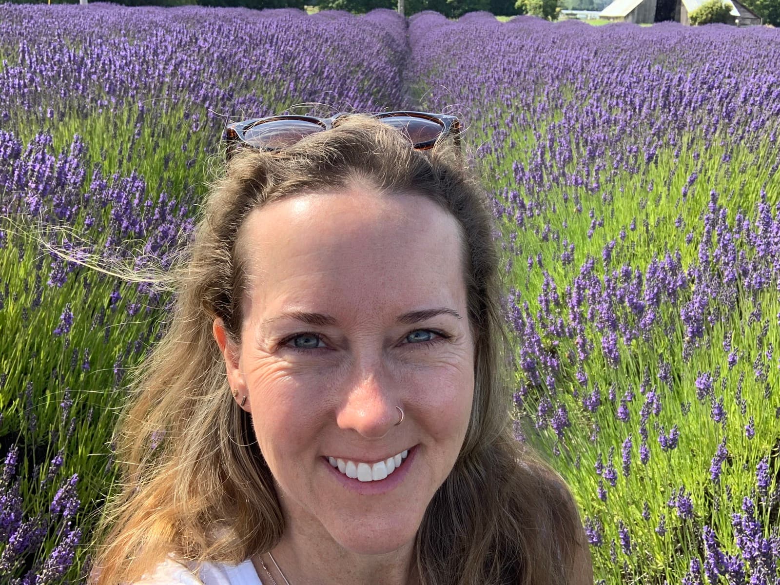 Kim smiling in a Woodinville lavender field, rows of blooming lavender behind her.